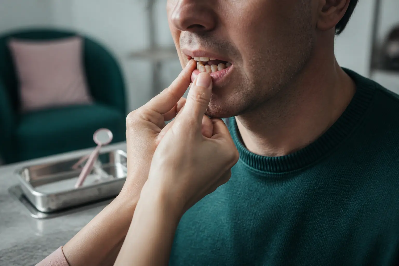 Dent qui bouge examinée par un dentiste en cabinet, gros plan sur la bouche et les mains du patient inquiété