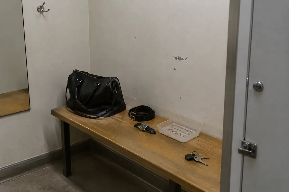 Banc de cabine avec un sac, une ceinture à boucle, une montre, des bijoux dans un bac et des clés