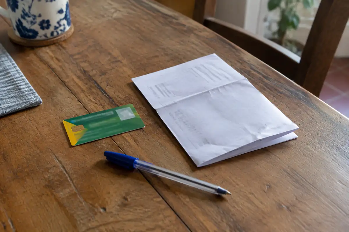 Carte d'implant en plastique et ordonnance pliée posées sur une table avec un stylo
